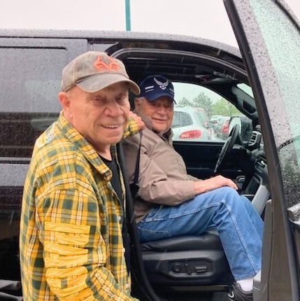 Volunteer driver holding truck door for transportation participant who is sitting in the vehicle