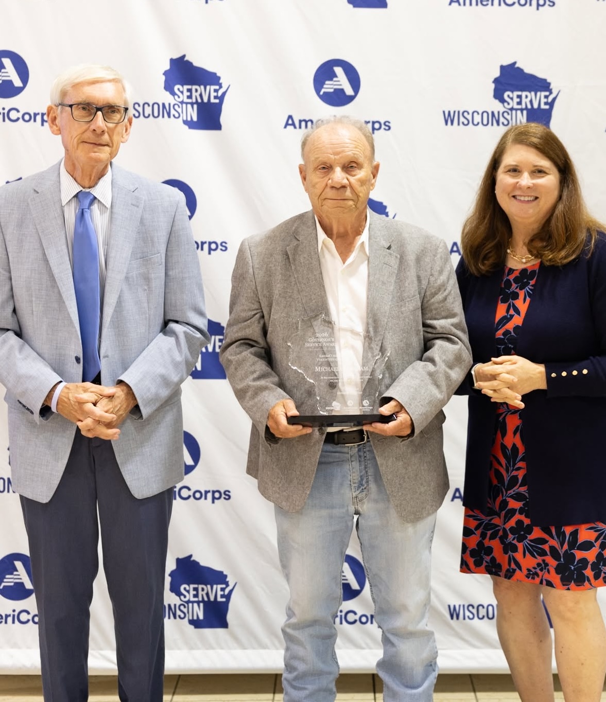 Photo of award recipient Michael Abraham holding Governor's Service Award. Michael is standing between Governor Tony Evers and Wisconsin Department of Administration Secretary Kathy Blumenfeld.