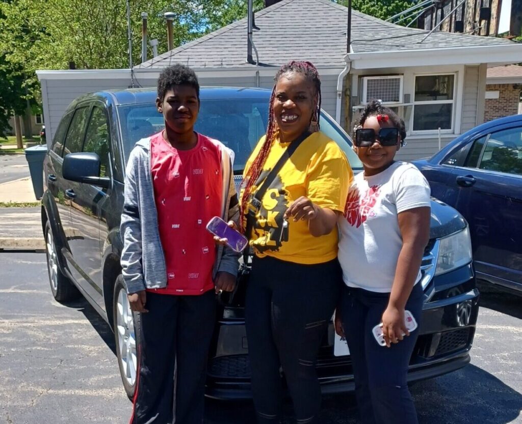 Woman and children standing next to their car they bought through ADVOCAP Work N Wheels