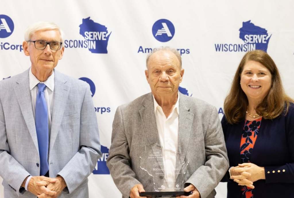 Photo of award recipient Michael Abraham holding Governor's Service Award. Michael is standing between Governor Tony Evers and Wisconsin Department of Administration Secretary Kathy Blumenfeld.