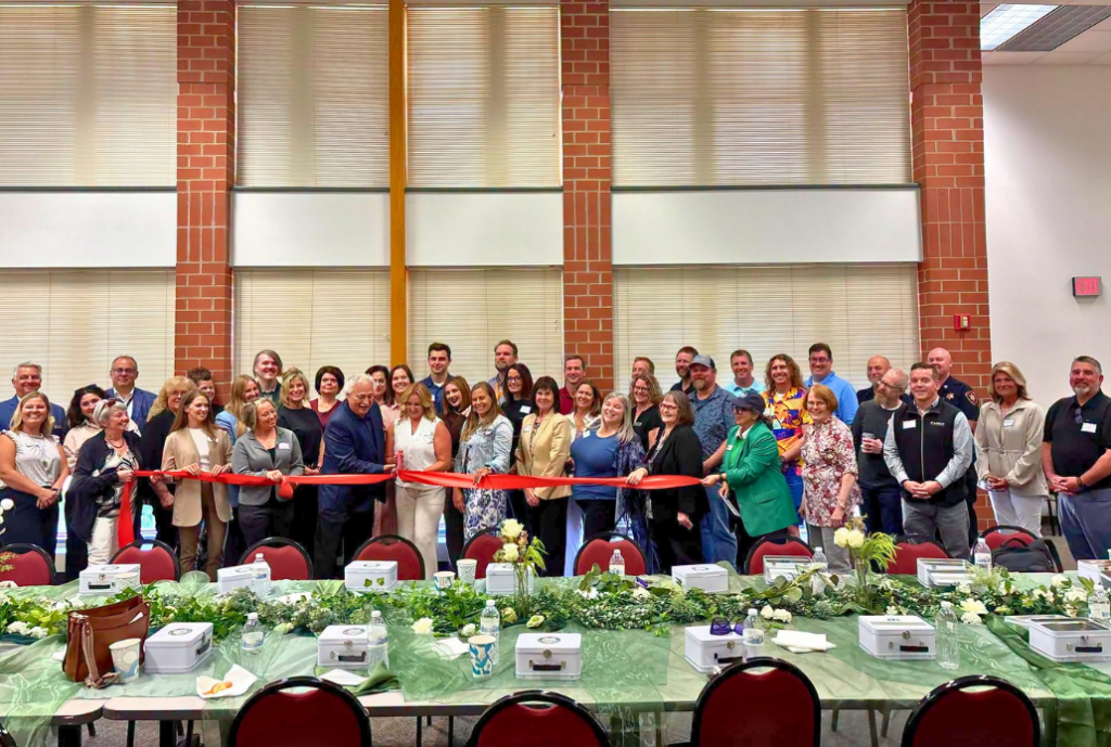 Group of all attendees standing behind ADVOCAP leadership for ribbon cutting ceremony