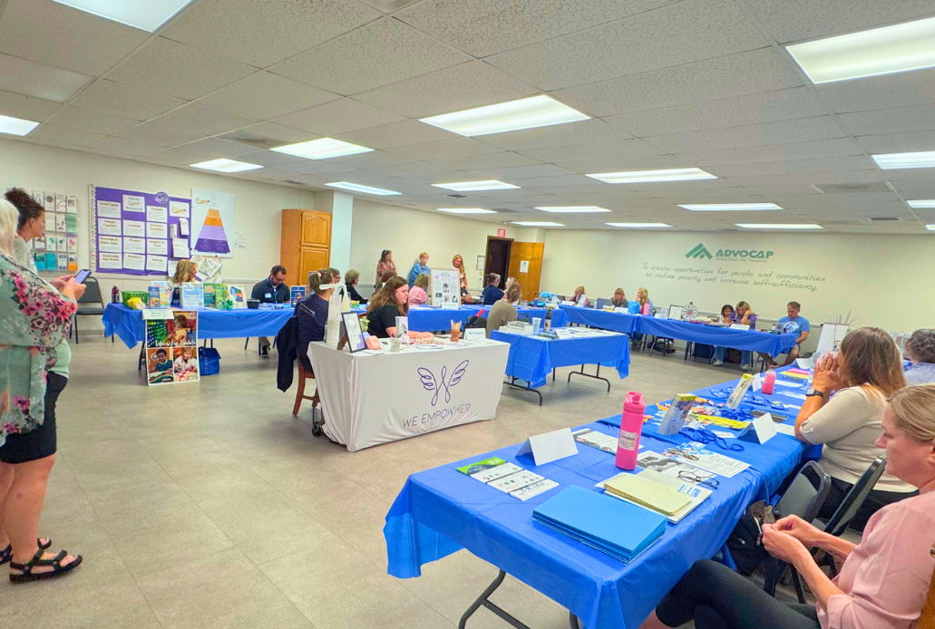resource booth tables set up around large ADVOCAP office room for resource fair with 18 organizations represented