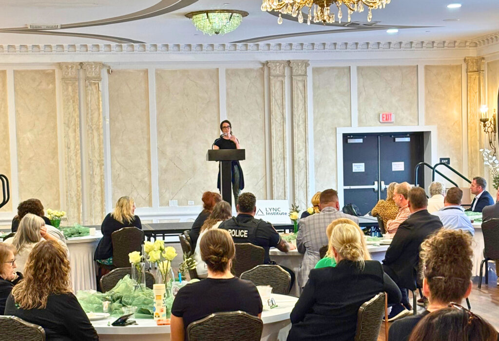 LYNC Institute Co-Founder and Chief Community Officer Meredith Bieri speaks to attendees from podium on stage