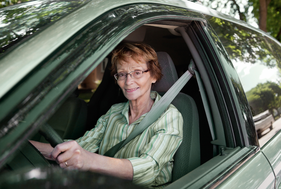 woman smiling in driver seat of vehicle and holding the steering wheel